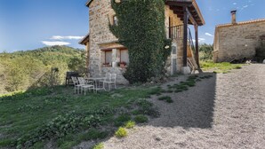 A stone building with a covered patio, a grill, and a view of the surrounding landscape. - Chalet 'Masia La Clariana' with Mountain Views, Private Pool and Wi-Fi (Castelltallat)