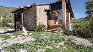 A stone house with a wooden staircase leading to a balcony. - Chalet 'Masia La Clariana' with Mountain Views, Private Pool and Wi-Fi (Castelltallat)