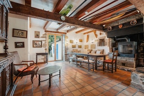 A rustic interior with exposed wooden beams, a stone fireplace, and a dining area with a table and chairs. - Holiday Home 'Maison Chapelle Du Verger' with Sea View, Shared Terrace and Private Garden (Cancale)