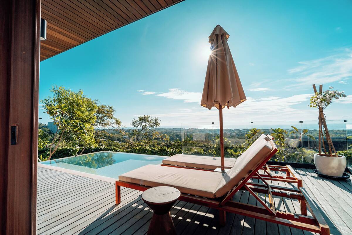Eine Holzterrasse mit Pool, Liegestühlen und einem Blumentopf.