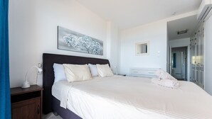 A bedroom with a large bed, a bedside table, a wall-mounted artwork, a mirror, and a wardrobe.