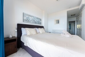 Une chambre à coucher avec un grand lit, une table de chevet, une œuvre d’art accrochée au mur, un miroir et une armoire.