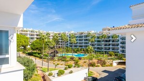 A residential building with a swimming pool, surrounded by greenery and palm trees.