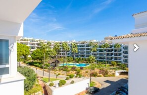 Un immeuble résidentiel doté d’une piscine, entouré de verdure et de palmiers.