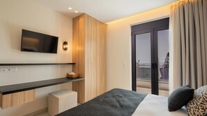 Une chambre d’hôtel moderne équipée d’un lit, d’un téléviseur à écran plat fixé au mur, d’une petite armoire en bois et offrant une vue sur l’extérieur grâce à une grande porte-fenêtre coulissante.