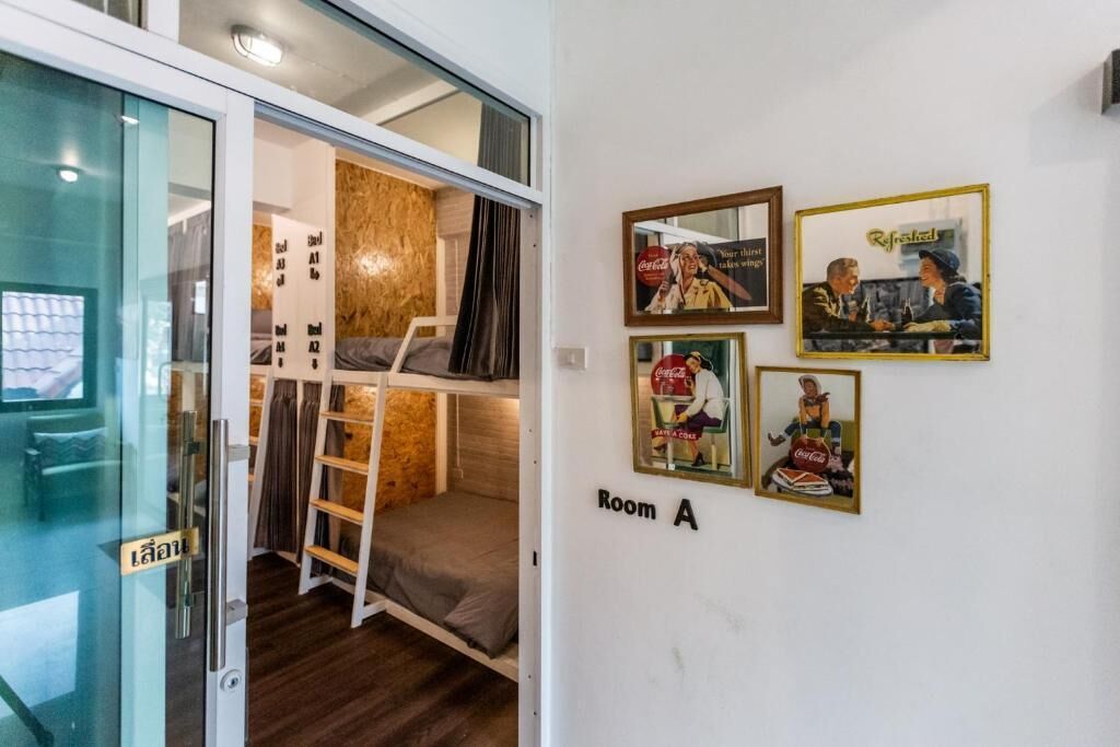 A compact room with a bunk bed, a small ladder, and a shelf. There are framed pictures on the wall, and a sign indicating 'Room A'.