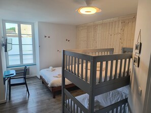A room with a bunk bed, a desk, a chair, a window with a view, and a wooden wall. - Hôtel Bar Restaurant La Marie Galante (Saint-Georges-d'Oleron)