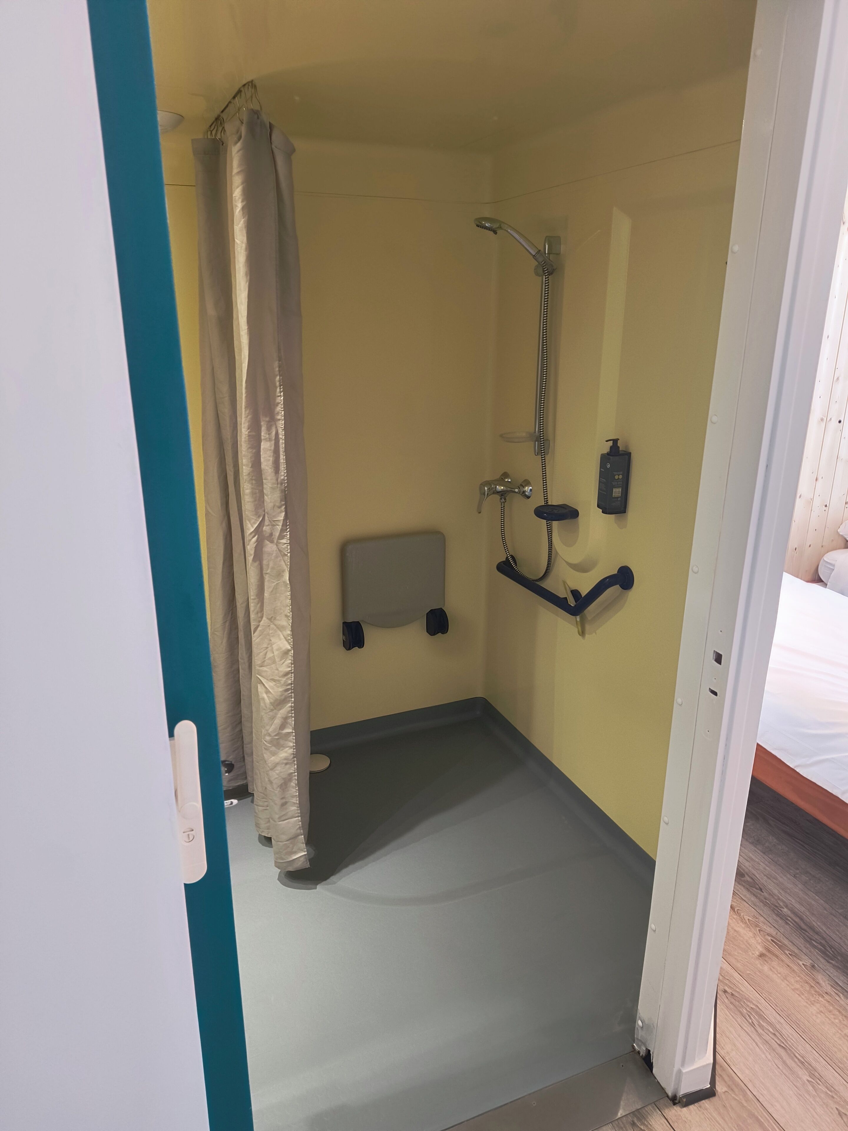 Un bagno piccolo e chiuso con doccia, un portasciuga e un dispenser per sapone.
