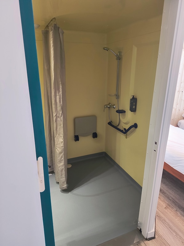 Ein kleines, abgeschlossenes Badezimmer mit Dusche, Handtuchhalter und Seifenspender.