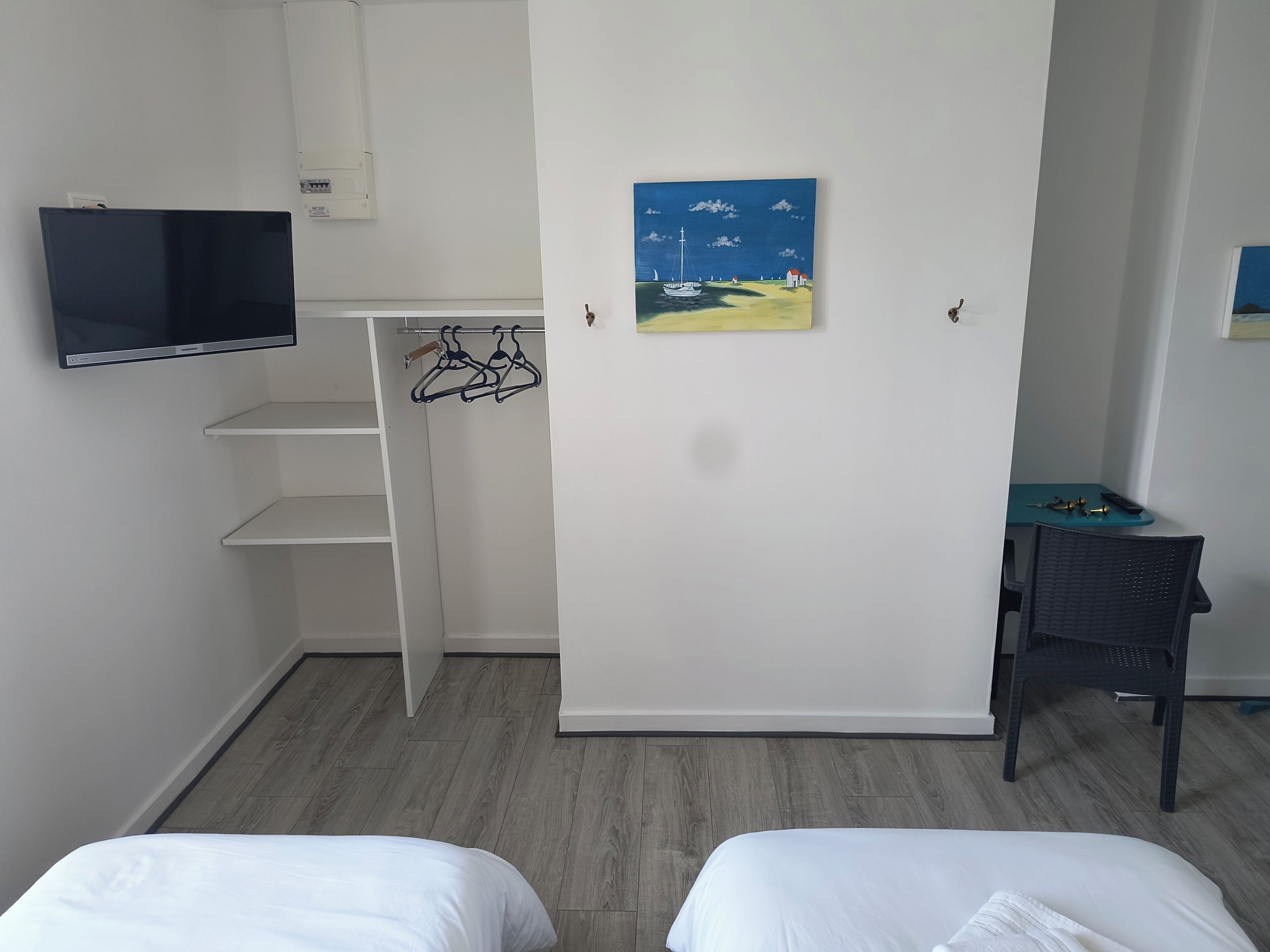 Un dormitorio con cama, televisión, armario, un cuadro y escritorio.