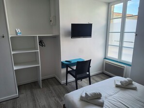 A hotel room with a bed, a desk, a chair, a TV, and a window. - Hôtel Bar Restaurant La Marie Galante (Saint-Georges-d'Oleron)