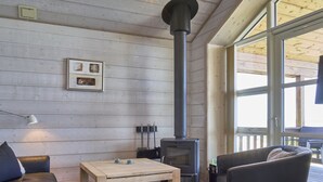 A cozy room with a wooden interior, a sofa, a table, a chair, a fireplace, and a window.