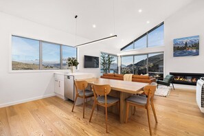 Enjoy a spacious living area with a dining table, sofa, and fireplace, offering stunning mountain views.