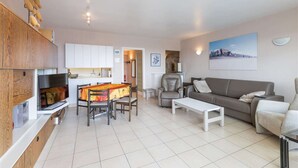 Uma sala de estar moderna com um sofá, uma mesa de centro e um espaço de jantar com mesa e cadeiras.