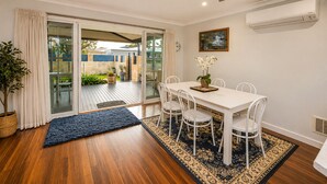A dining area with a white table, chairs, a ceiling fan, and a view through glass doors to an outdoor patio. - Sea Renity On Earnshaw (West Busselton)