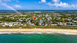 An aerial view of a coastal residential area with houses, a beach, and a visible rainbow. - Sea Renity On Earnshaw (West Busselton)