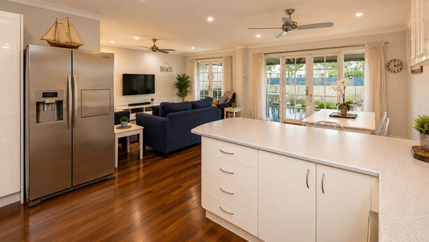 A modern kitchen with a built-in refrigerator, a dining area with a table and chairs, a living room with a sofa, and a balcony with a view. - Sea Renity On Earnshaw (West Busselton)