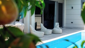 A poolside area with white cushioned chairs and a covered seating area. - Living Dream Villa Harmony (Antalya)
