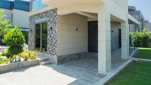 A modern two-story house with a flat roof, large windows, and a covered front porch. - Living Dream Villa Harmony (Antalya)