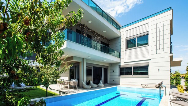 A modern two-story house with a swimming pool, outdoor seating, and a garden. - Living Dream Villa Harmony (Antalya)