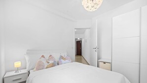 A modern bedroom with a bed, nightstand, and lamp. - Apartment White (Rovinj)