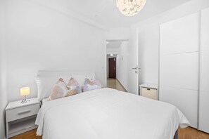 A modern bedroom with a bed, nightstand, and lamp. - Apartment White (Rovinj)