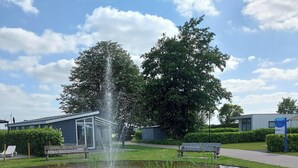 A circular water feature with a fountain in the center, surrounded by grass and a paved walkway.