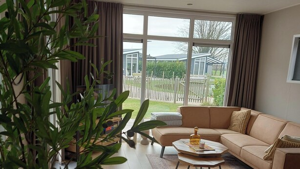 A modern living room with a beige sofa, a coffee table, and a potted plant.