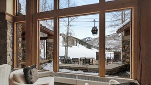 Une pièce chaleureuse avec de grandes fenêtres donnant sur un espace extérieur enneigé, agrémenté d’une terrasse et de chaises.