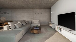 Een moderne woonkamer met een modulaire bank, een salontafel, een flatscreen televisie en een boekenkast.