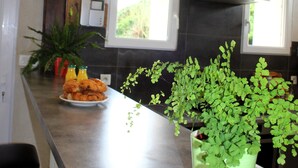 Una cocina con encimera de mármol, lámparas colgantes, campana extractora de acero inoxidable y una planta en maceta.
