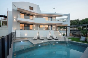 Una casa moderna de dos pisos con piscina, mobiliario exterior y una escalera que conduce al piso superior.