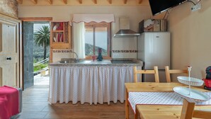 A kitchen with a wooden ceiling, a refrigerator, a sink, and a dining table with chairs.