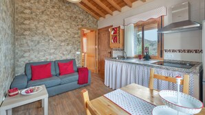 A cozy kitchen with a stone wall, wooden ceiling, and a dining area with a table and chairs.