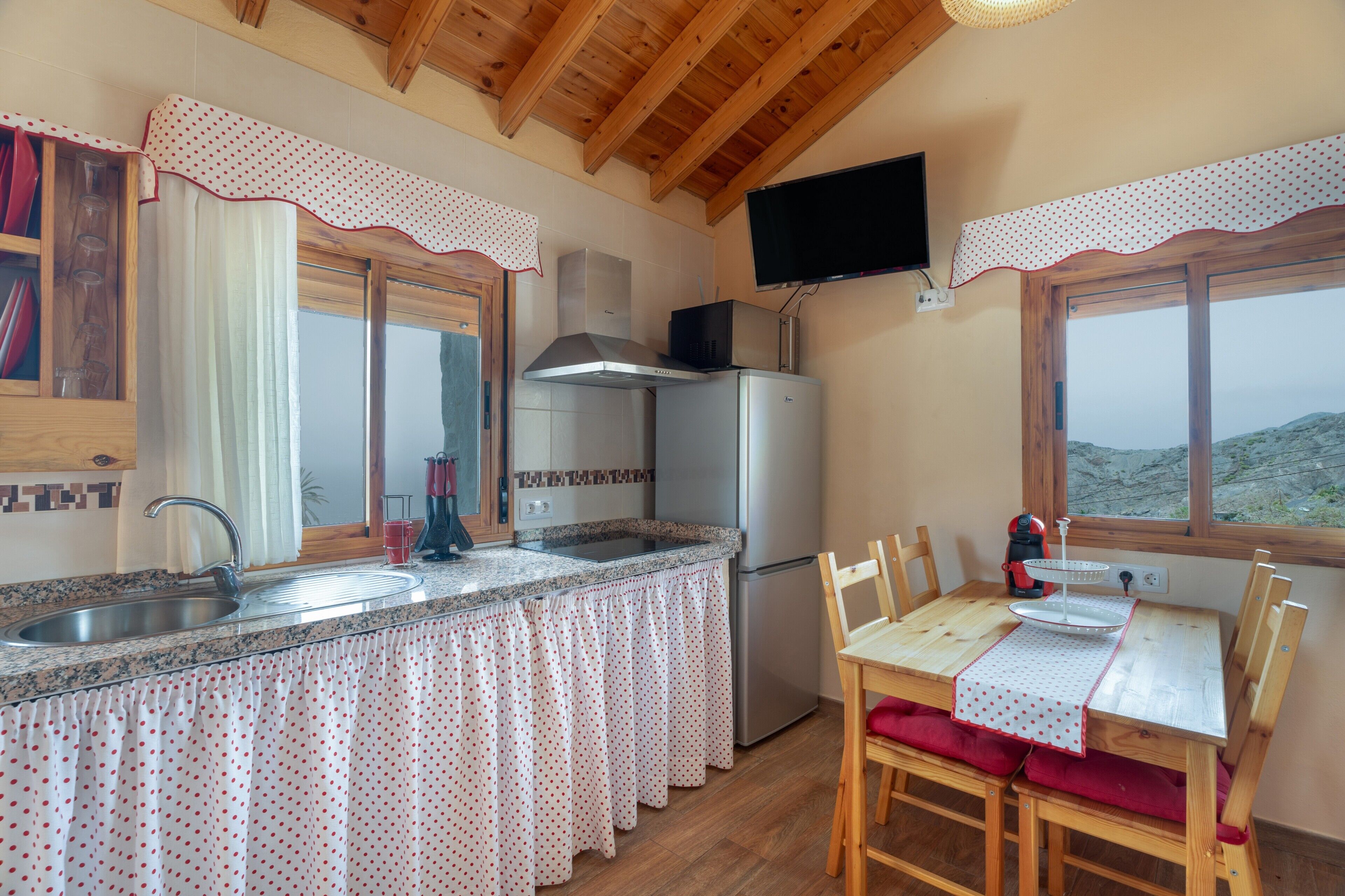 Una cocina con pileta, estufa y refrigerador, una mesa de comedor con sillas y una ventana con vistas.