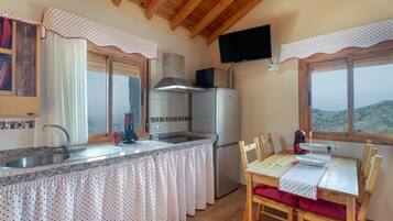 Una cocina con pileta, estufa y refrigerador, una mesa de comedor con sillas y una ventana con vistas.