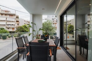 Enjoy the view from this balcony with a table and chairs, overlooking the surrounding residential area and lush greenery.