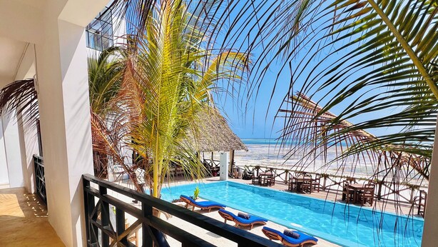 A pool area with lounge chairs and a thatched-roof structure. - Mia Boutique Hotel (Michamvi)