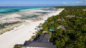 An aerial view of a beach resort with a white sandy beach, clear turquoise waters, and lush green vegetation. - Mia Boutique Hotel (Michamvi)