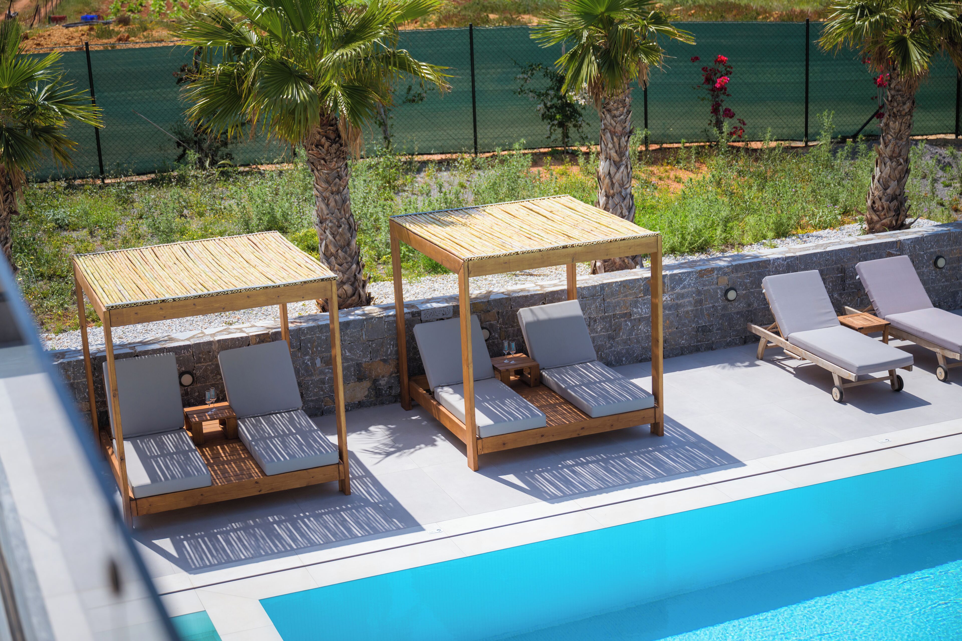 Un área junto a la piscina con cabañas de madera y sillones de descanso.