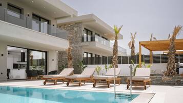 A modern pool area with lounge chairs and a stone pillar.