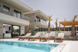 A modern pool area with lounge chairs and a stone pillar.