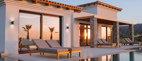 Un moderno resort con piscina, sillas de descanso y vistas a las montañas.