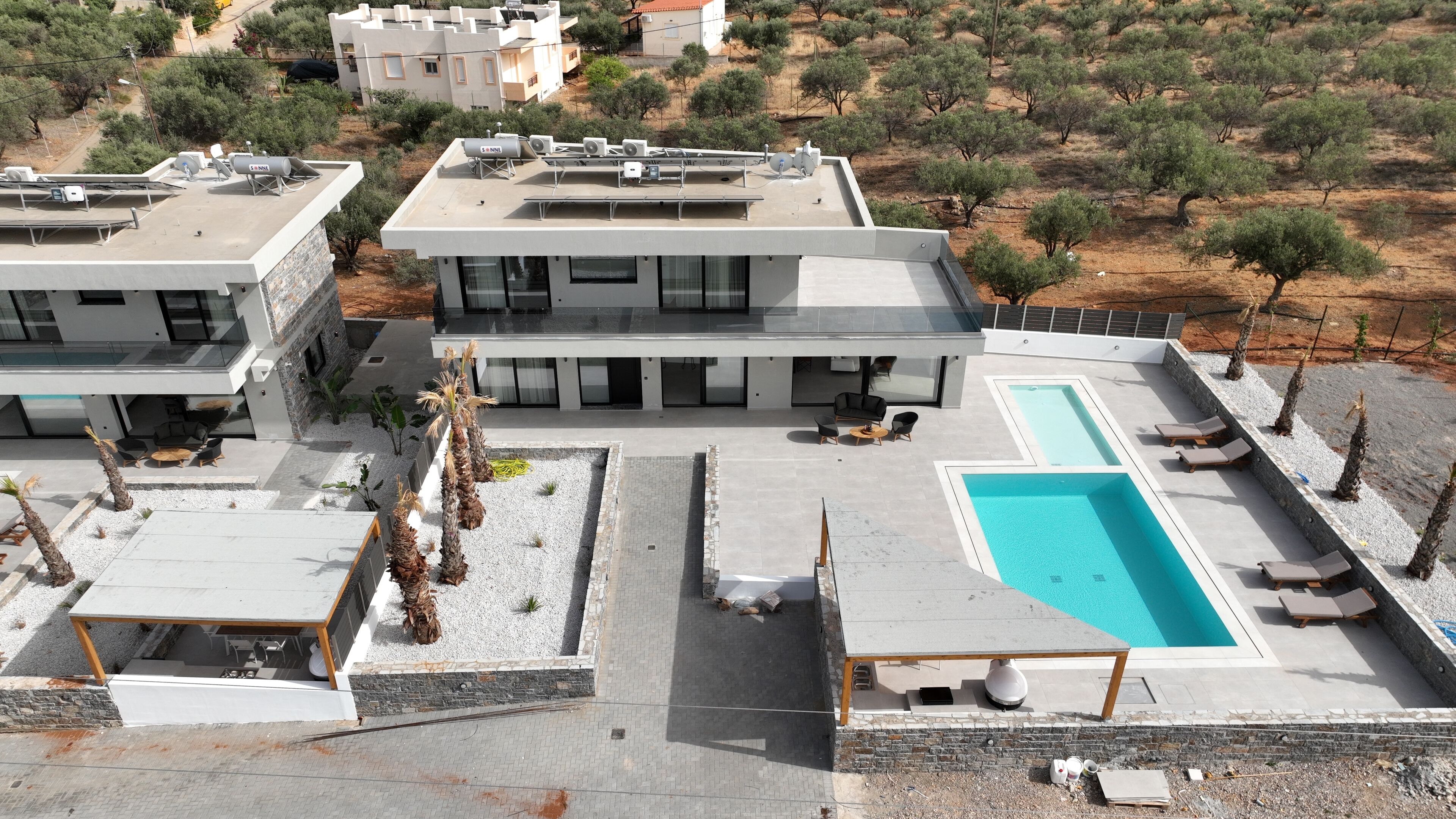 Un edificio moderno con piscina en la azotea, mobiliario de exterior y paneles solares.