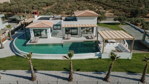 A modern villa with a swimming pool, outdoor seating, and a view of the surrounding landscape. - Temma Villas (Hersonissos)