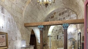 A spacious interior with a high arched stone ceiling, a central seating area with a sofa and coffee table, and a chandelier. - 1860 KADIEVİ (Ürgüp)