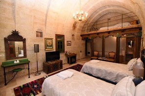 A room with two beds, a mirror, a television, and a chandelier. - 1860 KADIEVİ (Ürgüp)