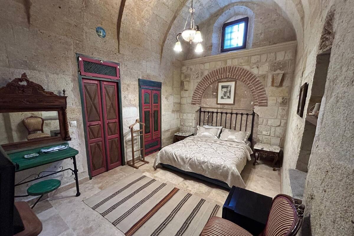 A bedroom with a bed, a desk, a chair, and a mirror.