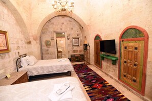 A room with two beds, a television, and a patterned carpet. - 1860 KADIEVİ (Ürgüp)