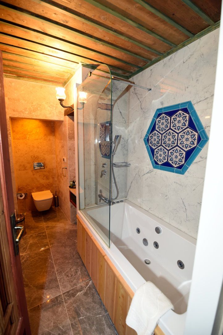 A bathroom with a glass-enclosed shower, a bathtub with multiple jets, and a toilet.